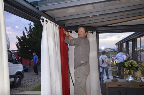 Installation de rideaux rouge et blancs avec oeillets noirs dans la vranda 